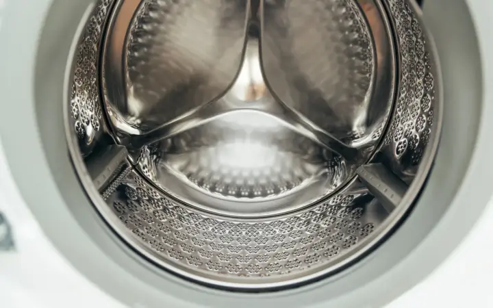 Close-up inside the stainless drum of a front-loading washing machine, the door seal around the opening
